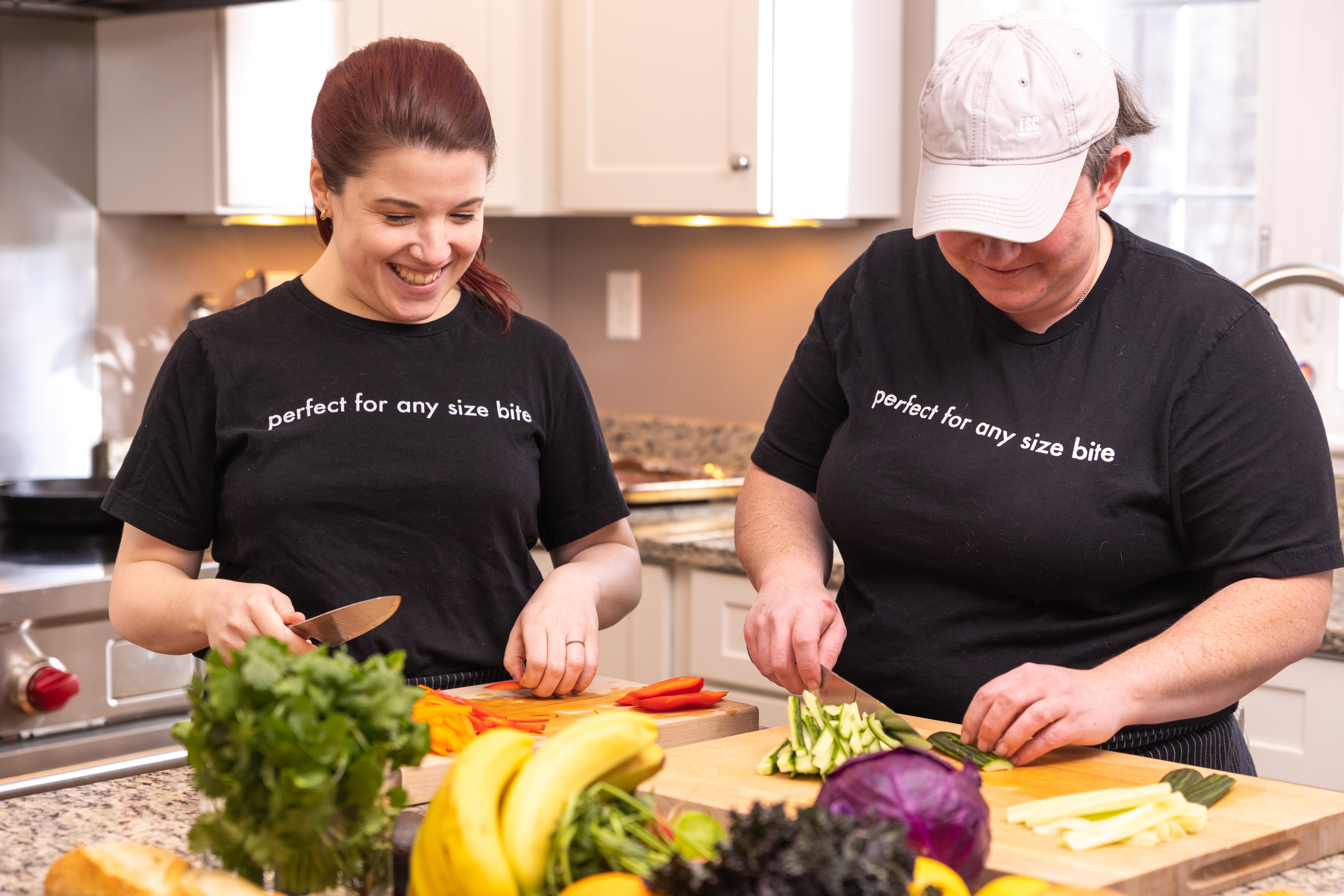 Chefs Laura and Amanda chopping fresh vegetables together at a kitchen counter