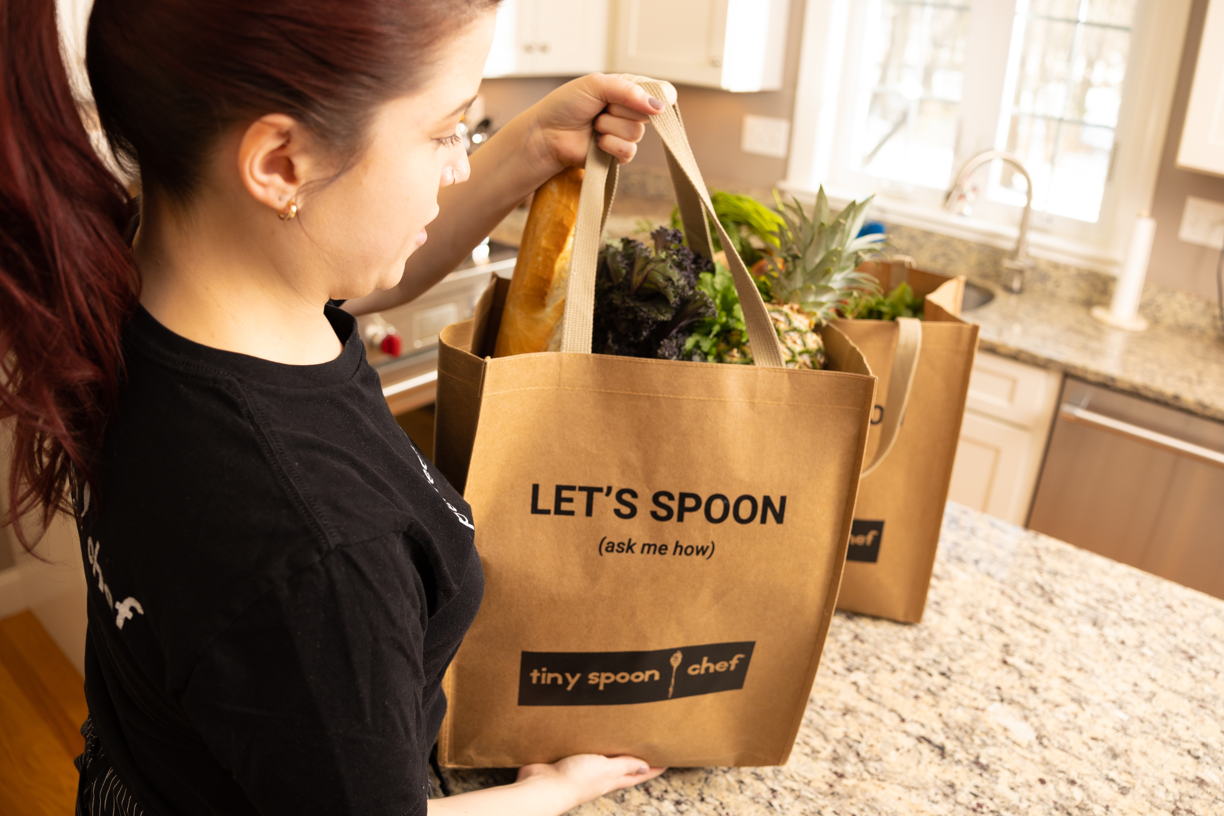 Chef Laura unpacking a Let's Spoon grocery bag of fresh produce in a client's kitchen