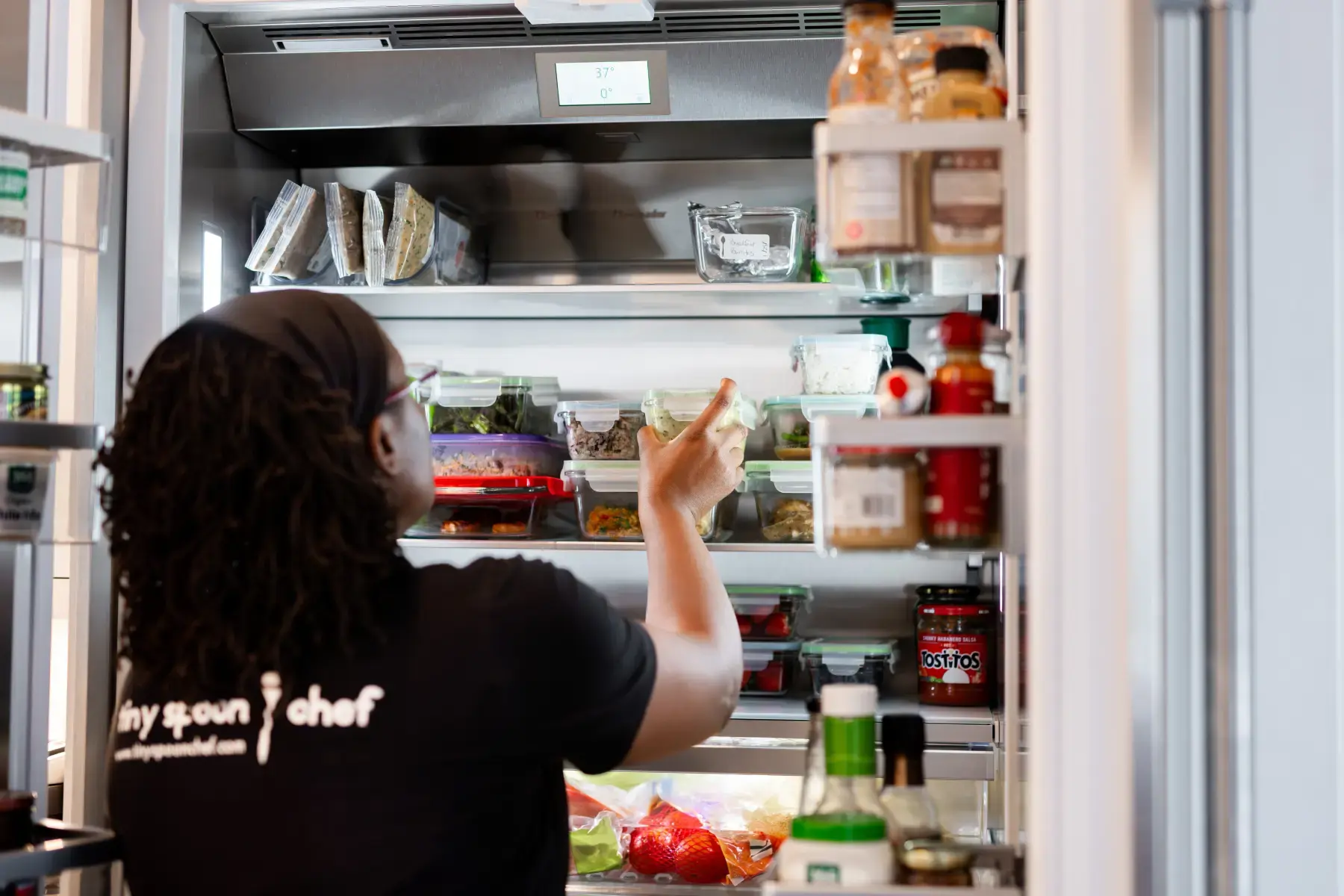 Tiny Spoon chef reaching into a client's stocked refrigerator